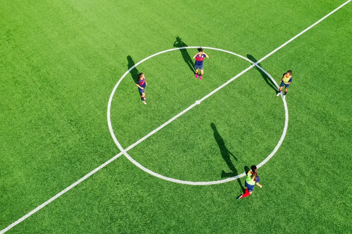 Vista aérea de jugadoras en el círculo central de un campo de fútbol